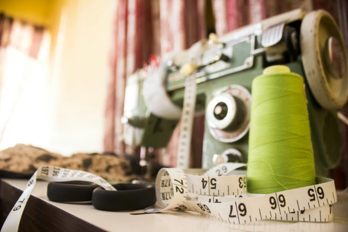 A sewing machine sitting on top of a table next to a measuring tape